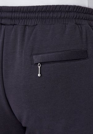 Pantalons de jogging bleu marine avec une poche arrière zippée, une taille élastique et un tissu doux et texturé. Design minimaliste.