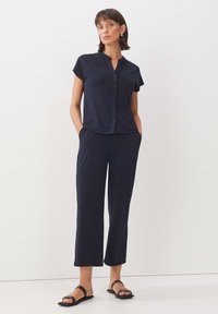 Navy blue, short-sleeve blouse with a button-up front and relaxed fit, paired with matching loose-fit pants; both made from smooth fabric.