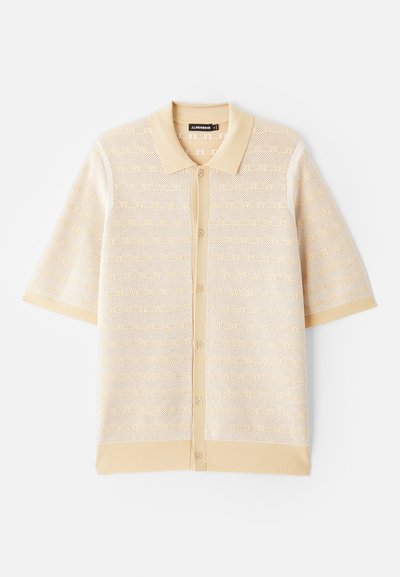 Beige Poloshirt mit kurzen Ärmeln, strukturiertem Strickmuster und Knopfleiste. Mit einem einfarbigen Kragen und kontrastierenden Akzenten.
