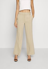 Beige weite Hosen mit vertikalen weißen Streifen, ausgestattet mit einem strukturierten Bund und seitlichen Taschen, aus leichtem Stoff gefertigt.