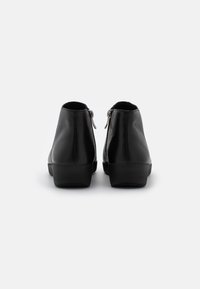 Botas de cuero negras hasta el tobillo con un diseño elegante, que cuentan con una textura suave, punta redonda y cierre de cremallera en la parte posterior. Tacón bajo y grueso.