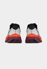 Ζευγάρι λευκών, πορτοκαλί και μαρόν αθλητικών παπουτσιών, εμφανιζόμενα από πίσω, με ορατή μαύρη εσωτερική επένδυση και υφή στις σόλες.