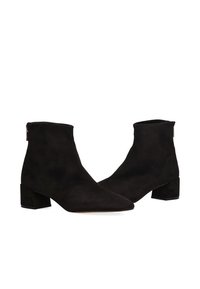 Botines de ante negro con punta fina y tacón bajo de bloque. Presentan una textura suave y un diseño minimalista con una discreta cremallera trasera.