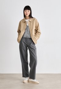 Light beige jacket, grey sweater, and grey wide-leg trousers. White sneakers with a textured sole. Simple design with minimal accents.