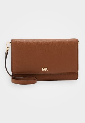Pochette bracelet en cuir marron texturé avec logo MK doré et bandoulière amovible sur fond blanc.