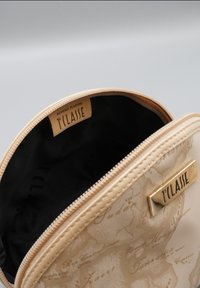 Borsa cosmetica beige con finitura lucida, caratterizzata da un motivo a mappa del mondo. L'interno è nero, con una targhetta logo dorata sulla parte anteriore.