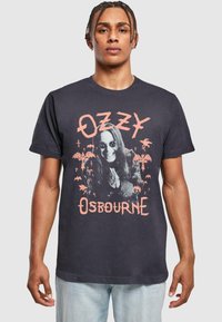 Sort bomulds T-shirt med et grafisk print af en person med langt hår i solbriller, omgivet af palmetræer og flagermus, med teksten "OZZY OSBOURNE".