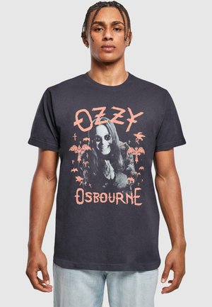 Sort bomulds T-shirt med et grafisk print af en person med langt hår i solbriller, omgivet af palmetræer og flagermus, med teksten "OZZY OSBOURNE".