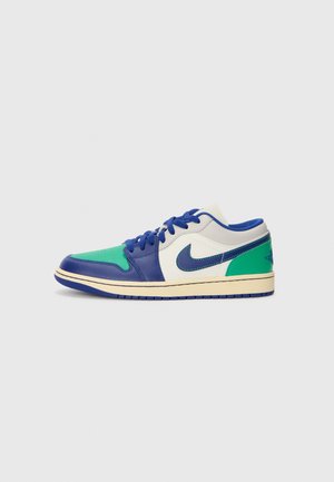 Flacher Sneaker mit grünen, blauen und weißen Lederpaneelen, blauen Schnürsenkeln und einer beigen Sohle mit einem blauen Nike-Swoosh-Logo.