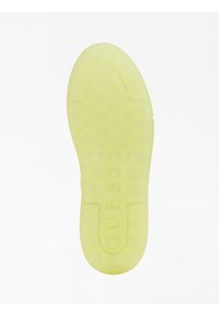 Semelle de chaussure de sport jaune translucide avec un motif de prise texturé et la marque "GUESS". Présente des bords arrondis et un design plat.