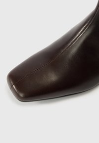 Pruun nahast pahkluu saabas terava ninaga, sileda tekstuuriga ja peene õmblusega mööda külge. Elegantne disain vooluva profiiliga.