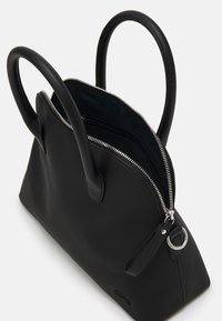 Sac à main noir texturé avec deux anses courbées et fermeture éclair argentée. Présente un petit détail de logo et une poche zippée à l'intérieur.