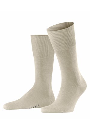 Beige cotton socks with ribbed cuffs, smooth texture, and reinforced toe and heel sections. Features minimal branding on the sole.