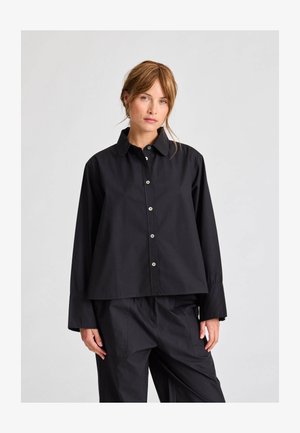 Zwarte overhemd met kraag, lange mouwen en een relaxte pasvorm, met contrasterende knopen en een gladde stoftextuur.