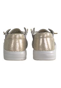 Gold metallic sneakers with a textured finish, white soles, and dual pull tabs at the heel, showcasing a scalloped edge design.