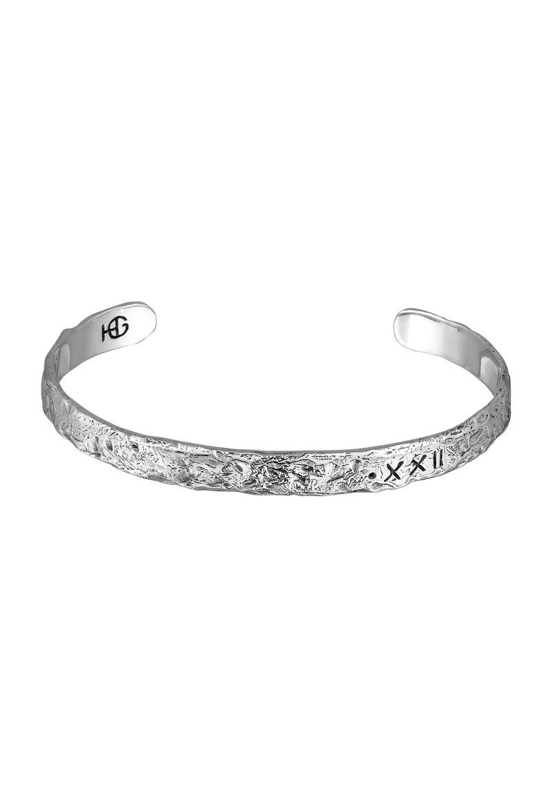 Silver bracelet with a textured, uneven surface, featuring engraved symbols. Open cuff design allows for easy wearing.