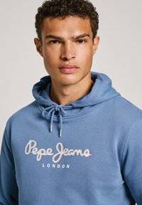 Sudadera con capucha azul y cordón, con un logotipo texturizado de "Pepe Jeans London" impreso en el pecho. Tejido suave con un corte holgado.