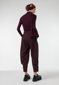 Bordeaux lange mouwtop gecombineerd met hoge taille, losse donkere bruine broek. Draag met zwarte plateau schoenen en een gemusterde hoofddoek.