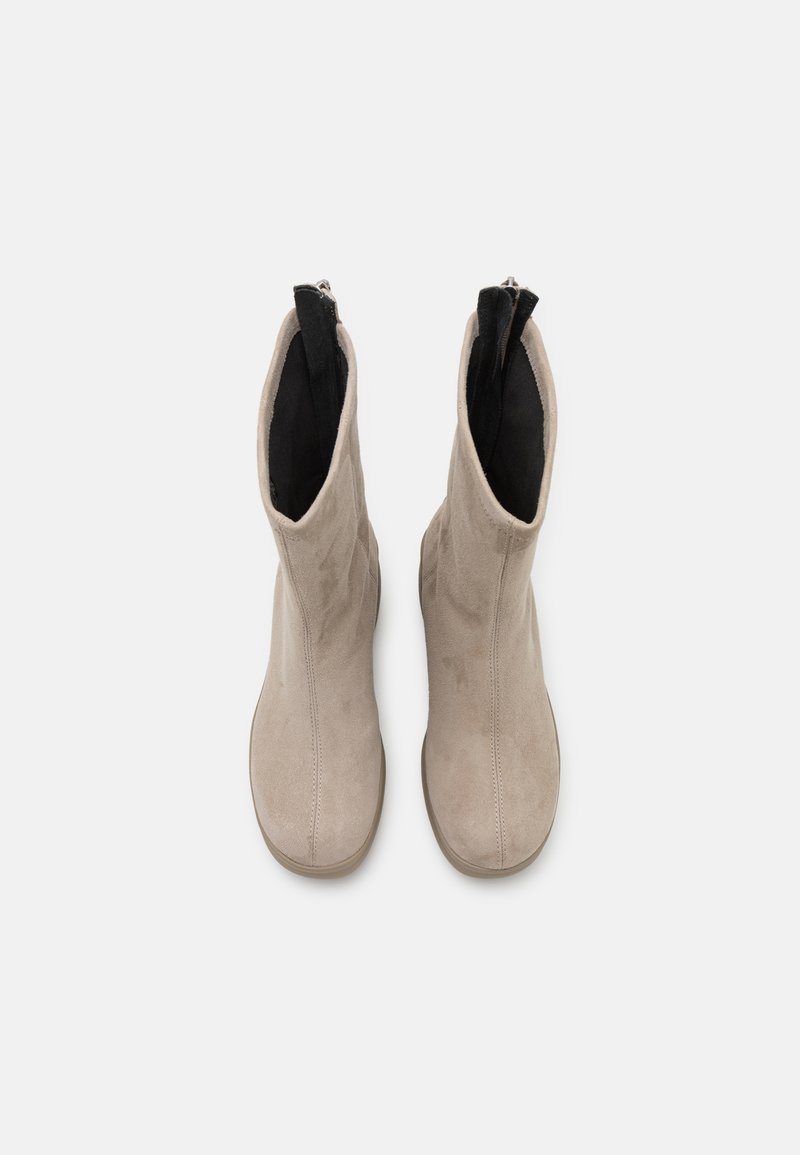 Beige Wildleder-Stiefeletten mit einer glatten Textur, elastischen Seiteneinsätzen und einem Reißverschluss auf der Rückseite für einfaches Anziehen.