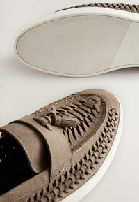 Gray leather slip-on shoes with woven pattern, round toe, and decorative tassel. White textured rubber sole for grip and stability.