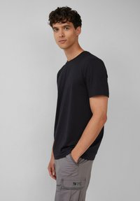 Czarna koszulka z krótkim rękawem w luźnym kroju, wykonana z miękkiej bawełny. Materiał ma gładką strukturę, a wzór jest prosty i uniwersalny.