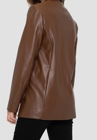 Brown faux leather blazer with a smooth texture, tailored fit, and clean lines. Features a simple collar and no visible hardware.