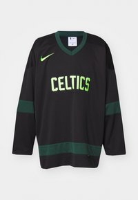Čierny dlhý rukáv dres s zelenými akcentmi a nápisom "CELTICS" v tučných písmenách. Obsahuje dizajn s výstrihom do V a logo Nike na ramene.