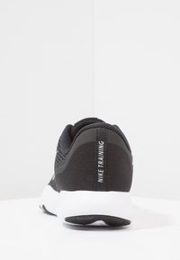 Scarpa da allenamento Nike in mesh nero con finitura testurizzata, dotata di suola bianca e linguetta del tallone con la scritta "NIKE TRAINING" in bianco.