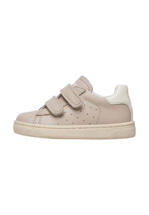 Zapatilla de cuero beige con dos tiras de Velcro, detalles perforados en los laterales, lengüeta blanca en el talón y suela de goma color crema.