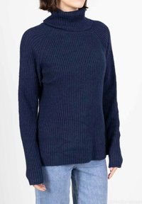 Pull à col roulé côtelé bleu marine avec manches longues, fabriqué à partir d'un tissu texturé ; coupe décontractée avec un col haut.