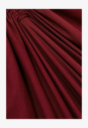 Mørkerød stof med en tekstureret overflade, der har lodrette folder, som skaber et lagdelt udseende. Glat og let blank finish.