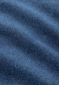 Tela de denims de color azul oscuro, texturizada con patrones de tejido visibles y una superficie suave y lisa. Pliegues ligeramente estirados crean profundidad.