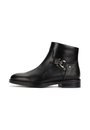 Bota corta de piel negra con tacón bajo, detalle de hebilla lateral y punta lisa y redondeada.