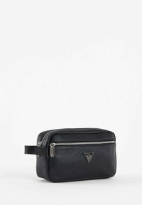 Beauty case in pelle nera con finitura testurizzata, zip argentata e logo triangolare sulla parte anteriore. Forma rettangolare compatta con manico per il trasporto.