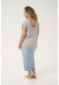 Grå kortærmet top med åben ryg designt, parret med en lyseblå denimnederdel. Glatte teksturer, afslappet pasform og mellemlang skæring.