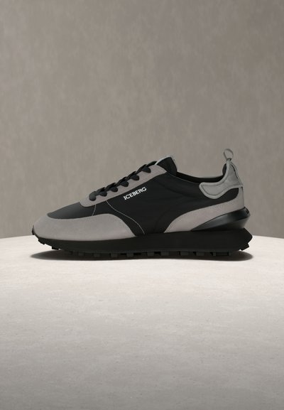 Μαύρο και γκρι αθλητικό παπούτσι με χαμηλό προφίλ, υφή στην σόλα και λογότυπο «ICEBERG» στην πλευρά, τοποθετημένο σε ουδέτερη επιφάνεια και φόντο.