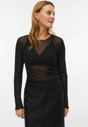 Black long-sleeve top made of sheer, textured fabric with a subtle shimmer. Features a V-neckline and frilled hem. Paired with a black skirt.