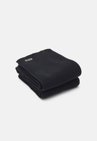 Zwarte geribbelde sokken, netjes opgevouwen, met een groen geborduurd logo. Zachte textuur met een comfortabele pasvorm.