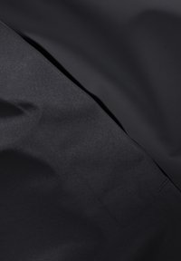 Schwarzer Stoff mit glatter Textur, der einen subtilen Glanz und Falten aufweist. Das Material zeigt eine einheitliche, tiefe Farbe ohne sichtbare Muster.