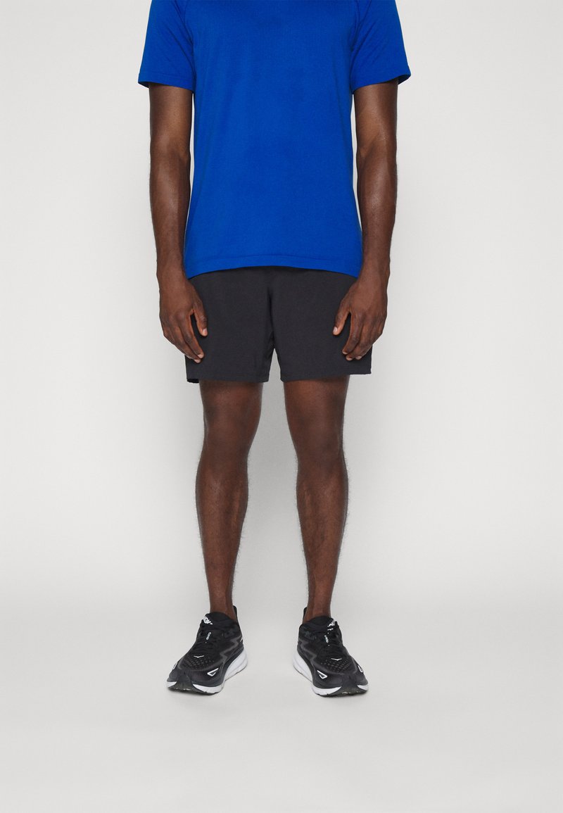 Blaues kurzärmliges Sportshirt, schwarze sportliche Shorts und schwarze Laufschuhe, alles für aktive Bekleidung konzipiert, mit minimalem Design und Farbkontrast.