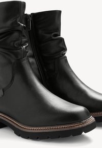 Bocanci negri din piele, cu un design lejer și fermoar lateral. Prezintă un finisaj texturat și o talpă din cauciuc rezistentă, cu o cusătură în contrast.