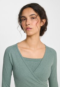 Top met lange mouwen en overslag in een gedempte groene kleur, gemaakt van geribd stof met een vierkante halslijn en een getailleerd ontwerp.