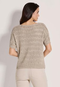 Licht beige gebreide trui met korte mouwen, met een losse pasvorm, open weefstructuur en horizontale strepen.