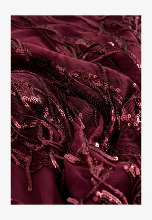 Material din plasă burgundă împodobit cu paiete împletite, creând o suprafață texturată și strălucitoare cu detalii și modele intricate.