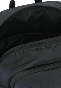 Zaino nero con un tessuto testurizzato, dotato di un compartimento con cerniera, interno aperto e spallacci doppi regolabili.