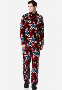 Tuta da sci con motivo a stelle nei colori rosso, blu e nero. Presenta maniche lunghe, chiusura frontale con cerniera e dettagli con logo. Realizzata in materiale resistente.