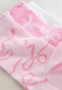 Calzini rosa e bianchi con una texture a coste, caratterizzati da motivi a scritta curva nei colori abbinati. La parte superiore presenta un design elasticizzato arricciato.