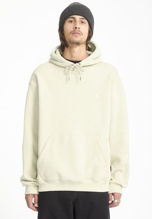 Lichtbeige hoodie met een kangoeroezak, trekkoordcapuchon, geribbelde manchetten en een klein logo op de borst, gecombineerd met zwarte broek.
