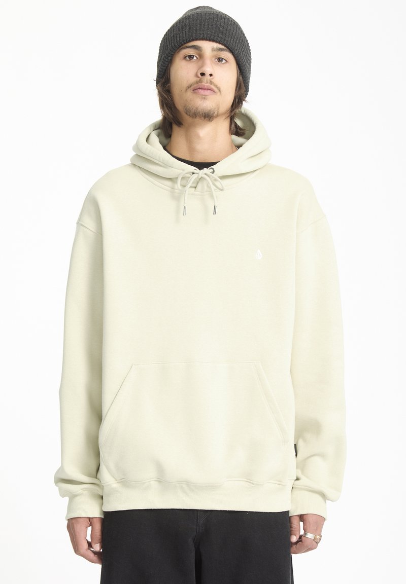 Lichtbeige hoodie met een kangoeroezak, trekkoordcapuchon, geribbelde manchetten en een klein logo op de borst, gecombineerd met zwarte broek.