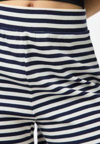 Námořnické modré a bílé proužkované legíny s měkkou, žebrovanou strukturou a elastickým pasem; obsahují boční kapsy pro praktičnost.